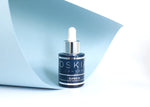 Oskia Super 16 Serum bottle against curled blue paper
