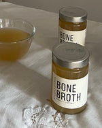 Atelier Nubio Bone Broth Chicken & Turmeric jars beside a bowl of warmed broth