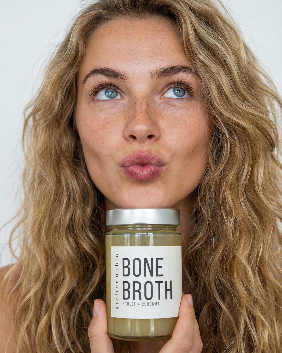 Atelier Nubio Bone Broth Chicken & Turmeric jar held by a model