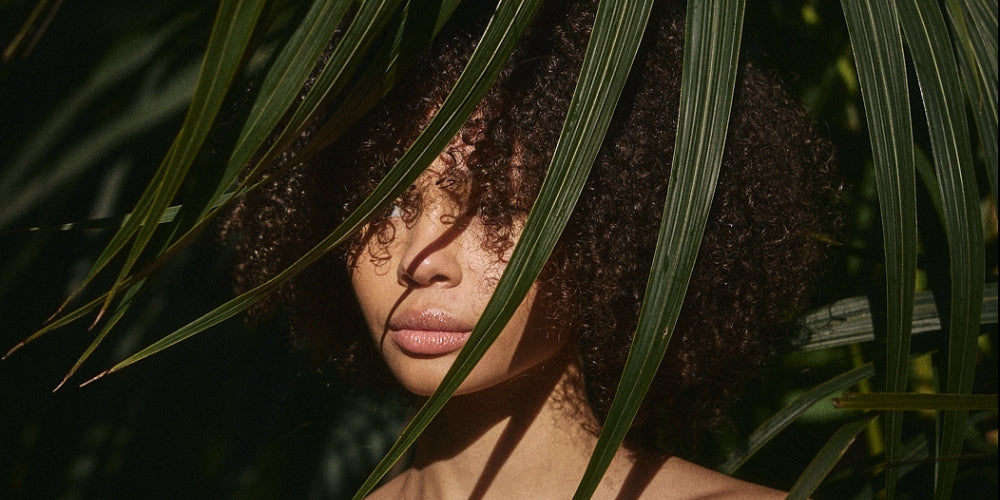 INIKA Organic - natural beauty, model behind palm fronds