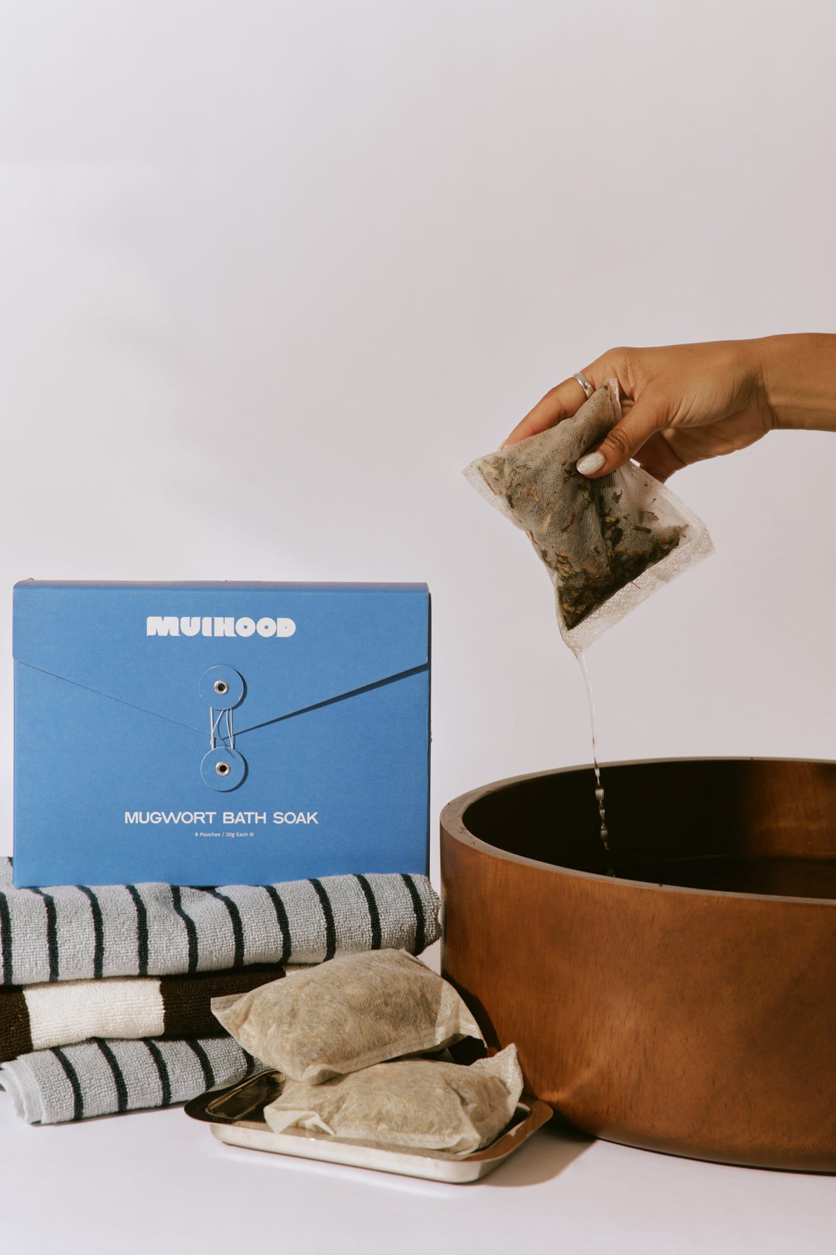 Muihood Mugwort Bath Soak blue box with herbal pouches and a wooden foot bowl