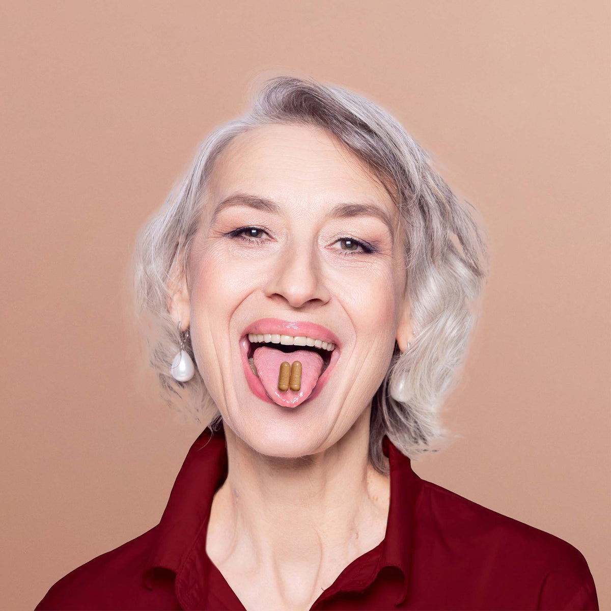 NAYDAYA The Menopause Capsule two capsules on a smiling woman's tongue